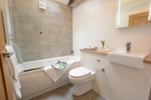 La salle de bains blanche est pourvue de toilettes et d'un lavabo. dans l'établissement Red Poll Barn, à Spexhall