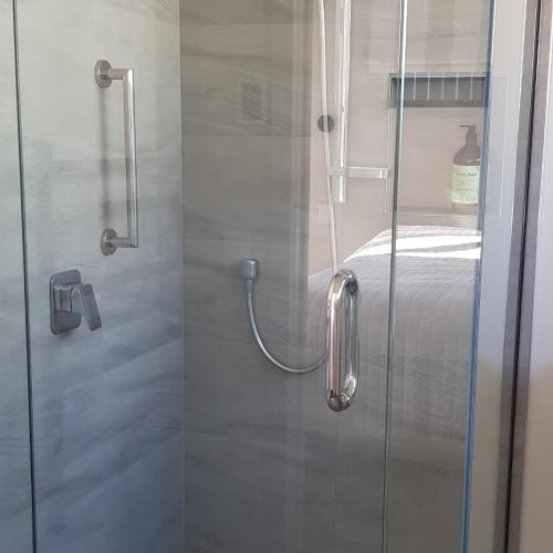 a shower with a glass door next to a bed at View on Kihilla in Richmond