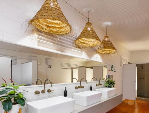 a bathroom with three sinks and two mirrors at Cooinda Lodge Kakadu in Jabiru