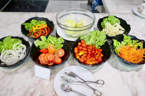 eine Gruppe von Schalen mit Gemüse auf einem Tisch in der Unterkunft Tinidee Hotel Bangkok Golf Club in Pathum Thani