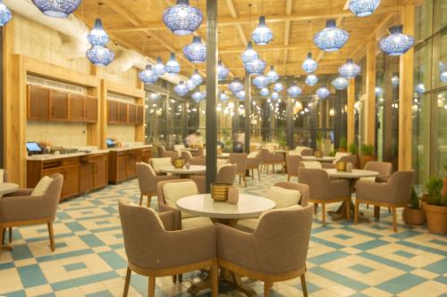a restaurant with tables and chairs and chandeliers at Citadines Abha in Abha