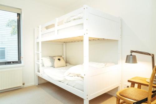 białe łóżko piętrowe w pokoju z biurkiem w obiekcie Candoux 4 w mieście Mount Buller