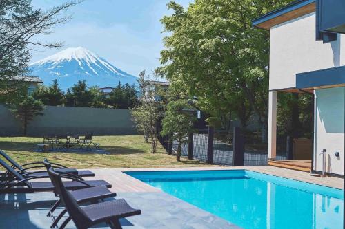 a mountain in the background of a house with a swimming pool at Villa Saison Fuji ヴィラ セゾン フジ in Fujikawaguchiko