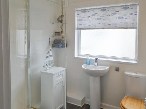 a bathroom with a sink and a toilet and a window at Tern House in Amble
