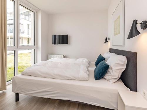 ein weißes Bett in einem Schlafzimmer mit einem Fenster in der Unterkunft Apartment Wendtorf XXVIII in Wendtorf