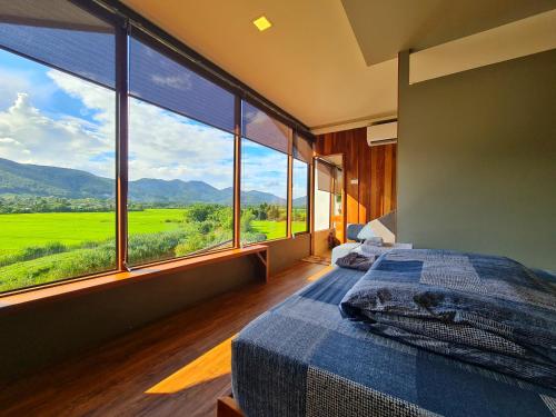a bedroom with a bed and a large window at Rock Onsen in Ban Huai Pa Hin