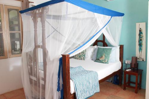 a bed with a canopy in a room at Driftwood Beach Lodge in Jambiani
