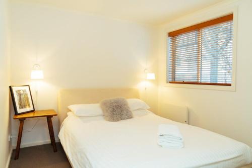 a bedroom with a white bed and a window at Reindeer 6 in Mount Buller