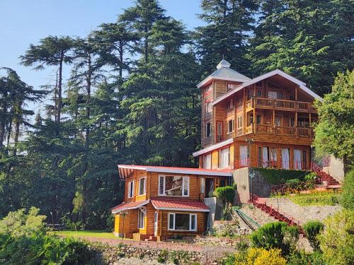 a large wooden house on a hill with trees at The Chalets Naldehra in Shimla