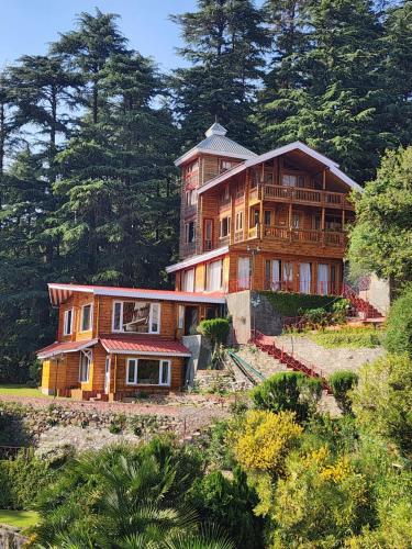 a large wooden house on a hill with trees at The Chalets Naldehra in Shimla