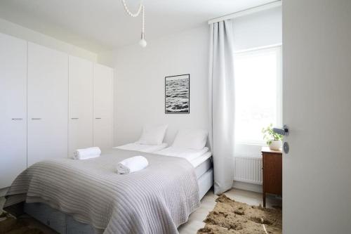 a white bedroom with a bed and a window at Fleminginkatu in Turku