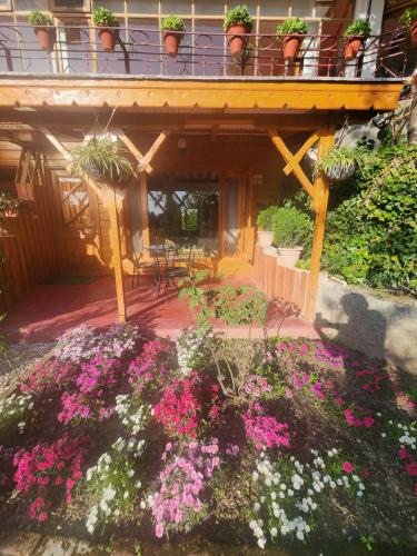 a patio with pink and white flowers in front of a building at The Chalets Naldehra in Shimla