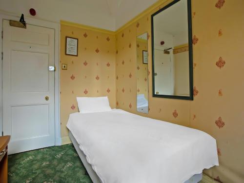 a bedroom with a white bed and a mirror at Great White Horse Hotel in Ipswich