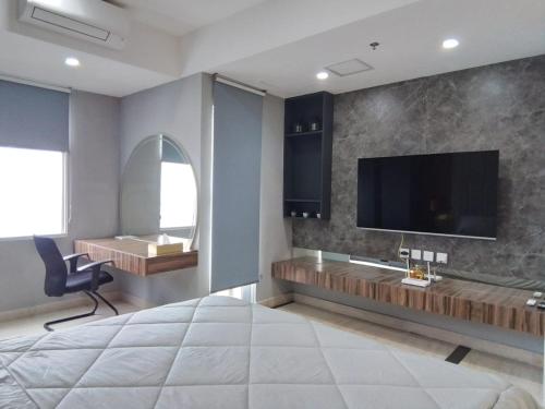 a bedroom with a large television and a desk at Apartment Medan Podomoro City Deli by OLS Studio in Medan