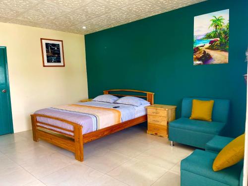 a bedroom with a bed and a blue chair at Hostal Tropicoco in Playas