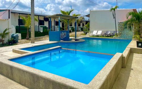 a pool with blue water in front of a house at Hostal Tropicoco in Playas