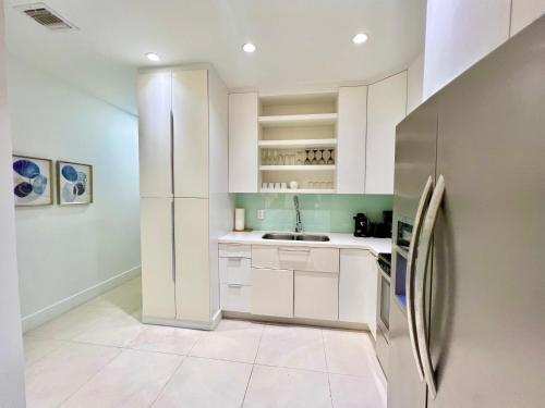 a kitchen with white cabinets and a refrigerator at SOBE MONARCH 2BEDROOM 2 BATH MODERN apt- WALK TO OCEAN DRIVE in Miami Beach