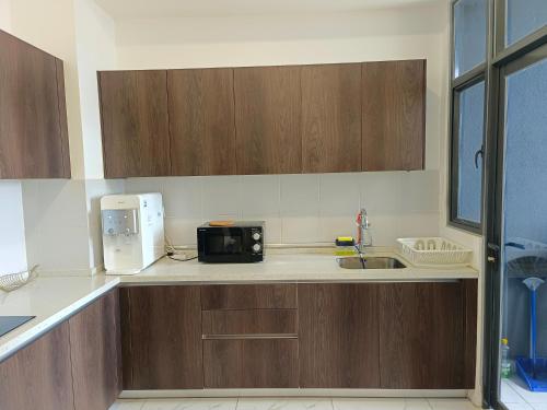 a kitchen with wooden cabinets and a microwave on a counter at Two Bedroom Troika Kota Bharu by AGhome in Kota Bharu