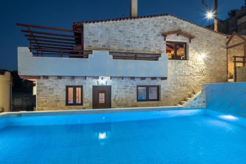 une villa avec une piscine la nuit dans l'établissement Draganigo Luxury Stone Houses 40 min from Matala, à Áno Moúlia