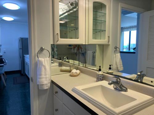 a bathroom with two sinks and a large mirror at Waikiki Banyan 1909 Amazing Views and Just Steps to the Beach in Honolulu