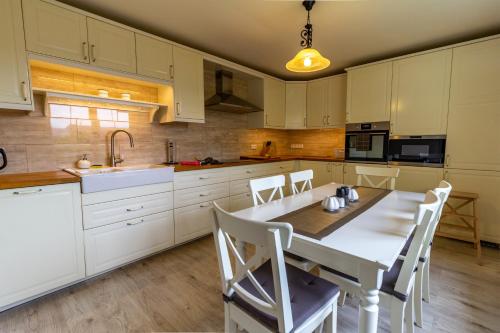 a kitchen with white cabinets and a table and chairs at Apartmánový dům Vilémovice in Vilémovice