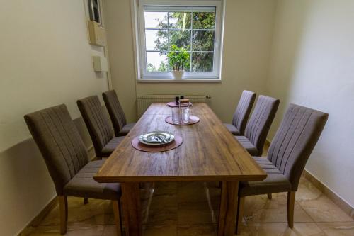 a dining room table with six chairs and a window at Apartmánový dům Vilémovice in Vilémovice