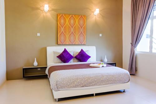 a bedroom with a large bed with purple pillows at Shamrock Beach Villas Batu Ferringhi Penang in Batu Ferringhi