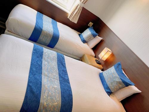 ein Schlafzimmer mit zwei Betten mit blauen und weißen Kissen in der Unterkunft Hotel KOYO Bekkan - Vacation STAY 37027v in Hashima