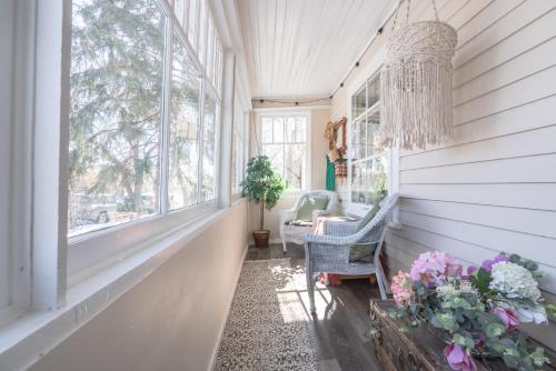 a porch with a chandelier and a chair and flowers at Craftsman's Loft - Heritage charm - AC - 5 min DT in Calgary