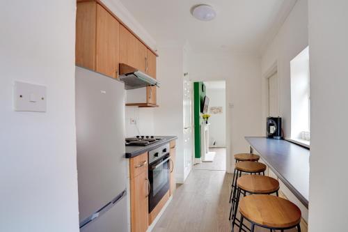 a kitchen with wooden cabinets and bar stools at Modern and Spacious 3-Bedroom House - Free Parking, Fast Wi-Fi, Ideal for up to 7 Guests in Houghton le Spring