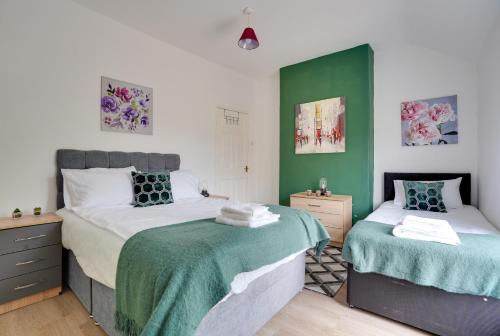 Duas camas num quarto com paredes verdes e brancas em Modern and Spacious 3-Bedroom House - Free Parking, Fast Wi-Fi, Ideal for up to 7 Guests em Houghton le Spring