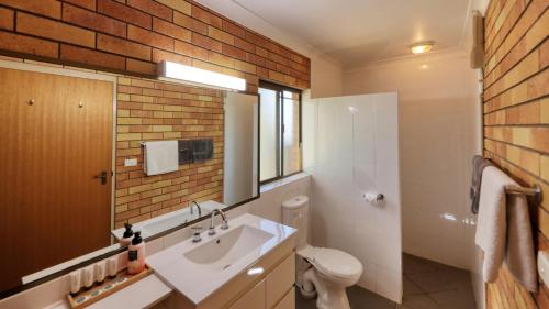 baño con lavabo blanco y pared de ladrillo en Merino Motor Inn, en Saint George