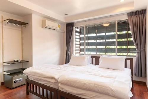 - une chambre avec un lit doté de draps blancs et une fenêtre dans l'établissement 420 House- up to 10 guests in central Bangkok., à Bangkok