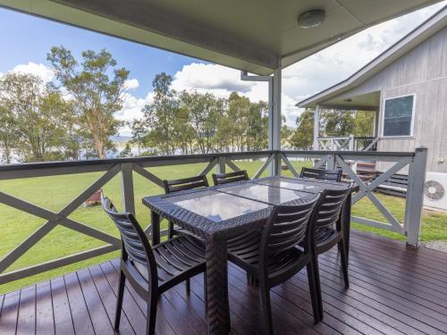 una mesa y sillas en una terraza con vistas a un campo en NRMA Lake Somerset Holiday Park, en Kilcoy