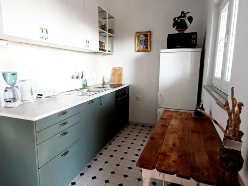 La cuisine est équipée de placards bleus et d'un réfrigérateur blanc. dans l'établissement Apartments Starshine & Lighthouse, à Zečevo