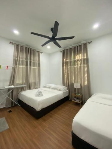 a bedroom with two beds and a ceiling fan at Kuala Kedah Pool Cottage in Kuala Kedah