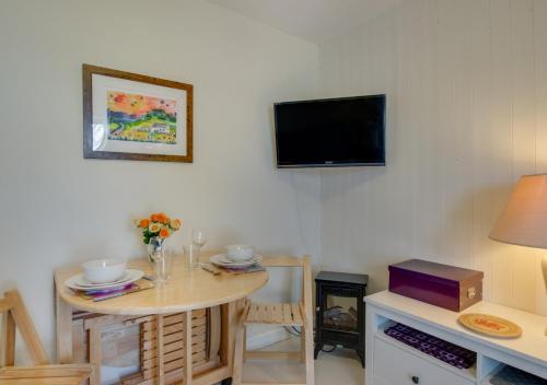 a living room with a table and a tv on the wall at Eluned Tresaith in Penbryn