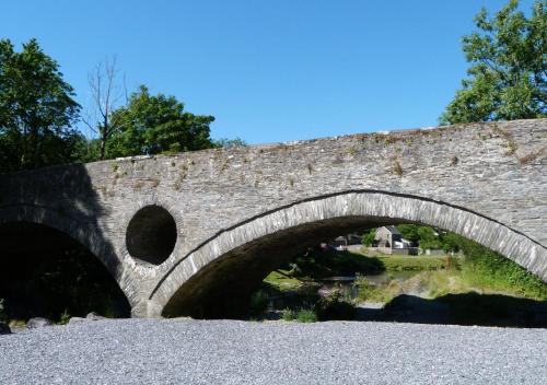 uma ponte de pedra sobre um corpo de água em Eluned Tresaith em Penbryn