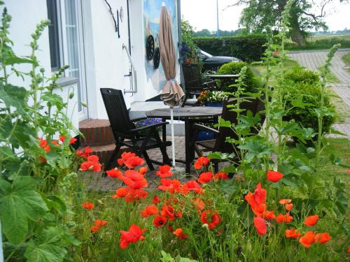 una mesa y sillas en un jardín con flores rojas en Ferienhaus mit Boddenblick, en Middelhagen