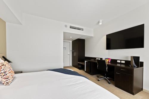 a bedroom with a bed and a desk and a tv at Lithgow Workies Club Motel in Lithgow