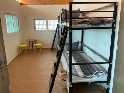 a room with three bunk beds and a table at Guesthouse Comfort Place in Buan