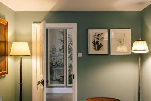 Gardener's House - Hawarden Estate في Hawarden: غرفة بجدران خضراء وثلاث صور على الحائط