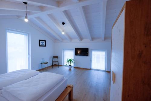 a bedroom with a white bed and a wooden floor at Casa Carolina in Levico Terme