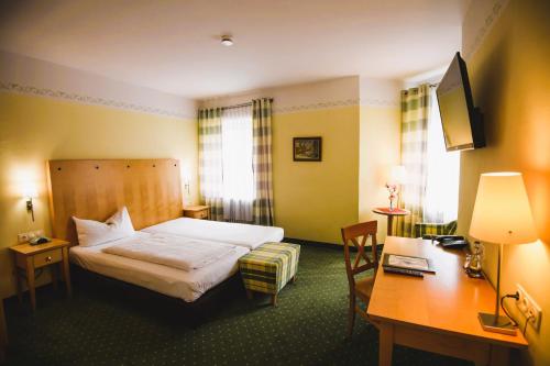 a hotel room with a bed and a desk at Hotel Rosenheimer Hof in Traunstein