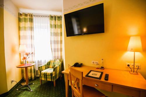 a hotel room with a desk and a television on the wall at Hotel Rosenheimer Hof in Traunstein