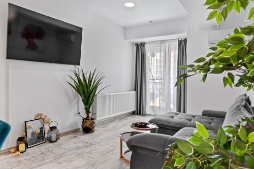 un salon avec un canapé et une télévision sur un mur dans l'établissement Old Town Hideaway - 5 Min Walk to Palace of Parliament and Old City - Best Neighborhood, à Bucarest