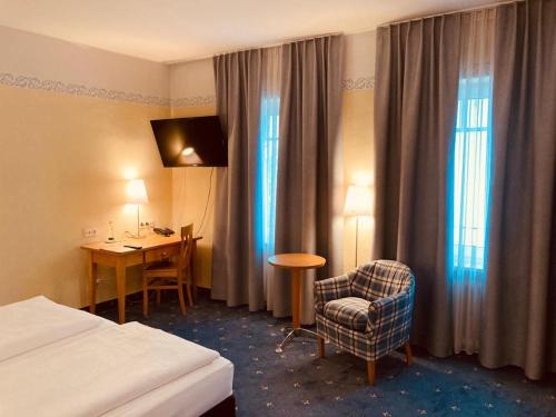 トラウンシュタインにあるHotel Rosenheimer Hofのベッド、デスク、椅子が備わるホテルルームです。