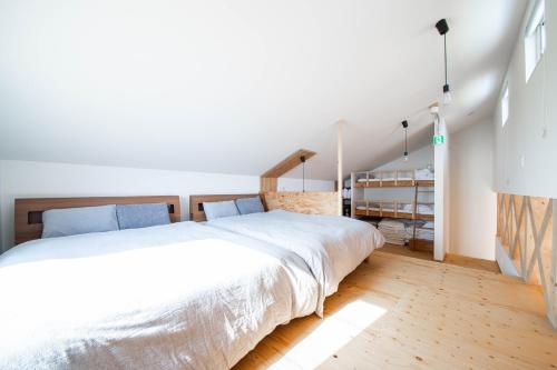 a bedroom with a large white bed and wooden floors at Sunny SIDE HOUSE in Atsuta