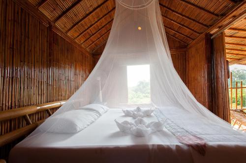 Bett in einem Zimmer mit Moskitonetz in der Unterkunft Phuree Hut in Ko Phayam