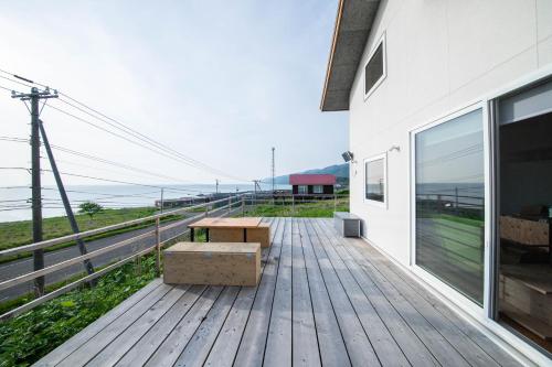 a wooden deck with a bench on the side of a building at Sunny SIDE HOUSE in Atsuta